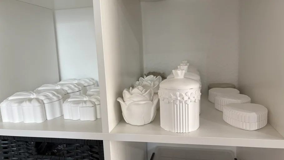 Weiße Keramikbehälter auf Regalen ausgestellt.