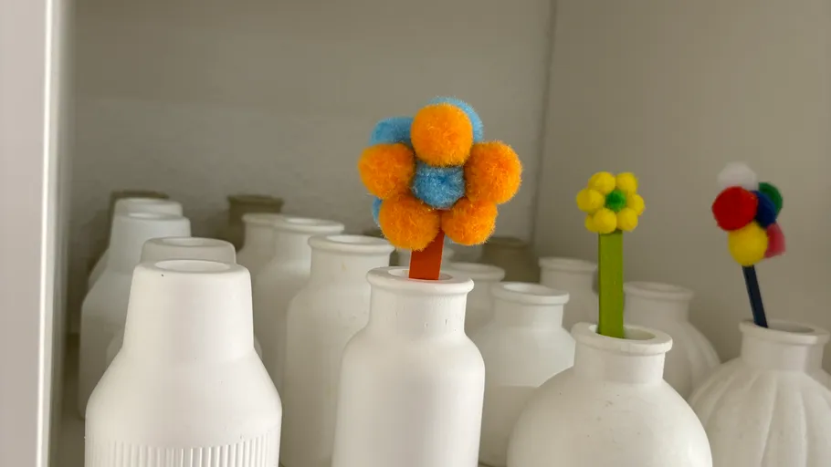 Bunte Pompons-Blumen in weißen Vasen.