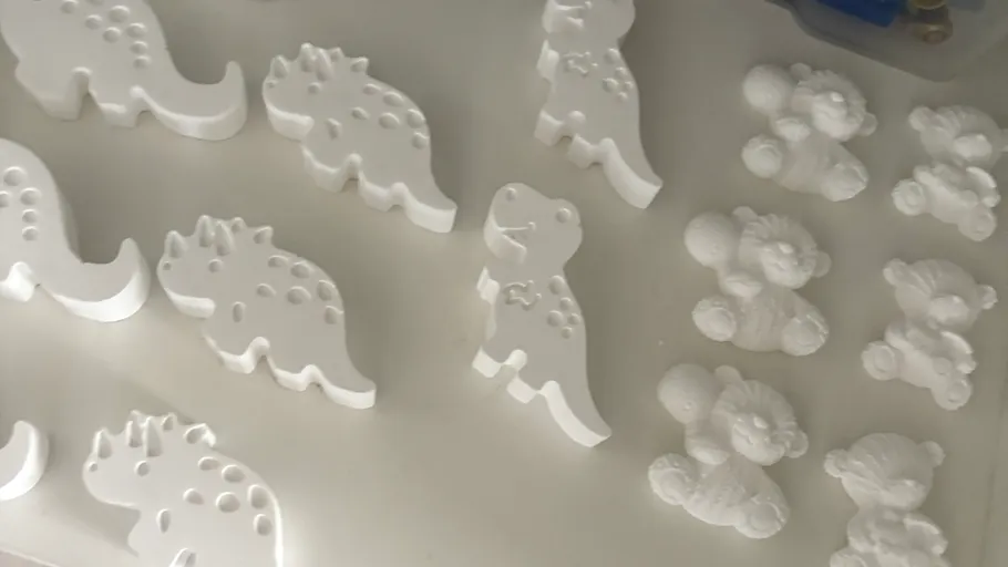 Weiße Dinosaurier- und Teddybärfiguren auf Oberfläche.