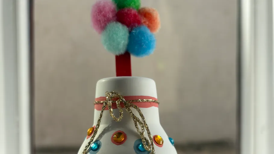 Decorative bottle with colorful pom-poms on top.