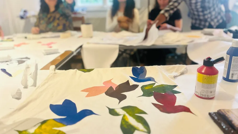 Painted T-shirt on table; people gathered around.