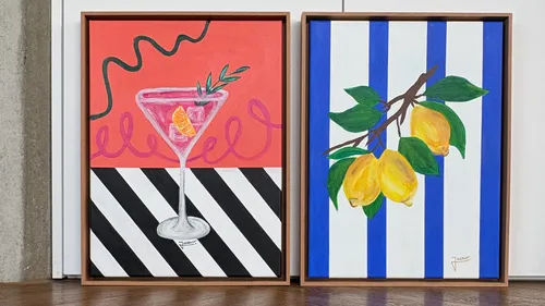 Two colorful framed paintings on floor.