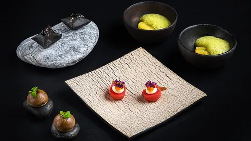 Gourmetgerichte kunstvoll auf schwarzem Hintergrund arrangiert.