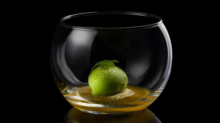 Green sphere inside a glass bowl, black background.