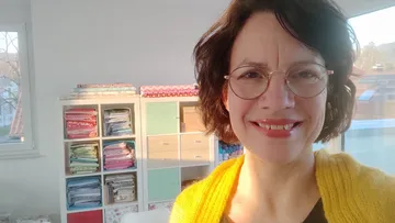 Woman smiling in a room with fabric shelves.