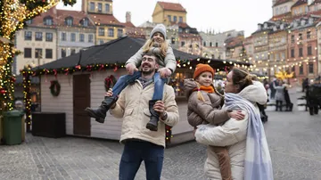 Familie genießt Weihnachtsmarkt mit Lichtern.