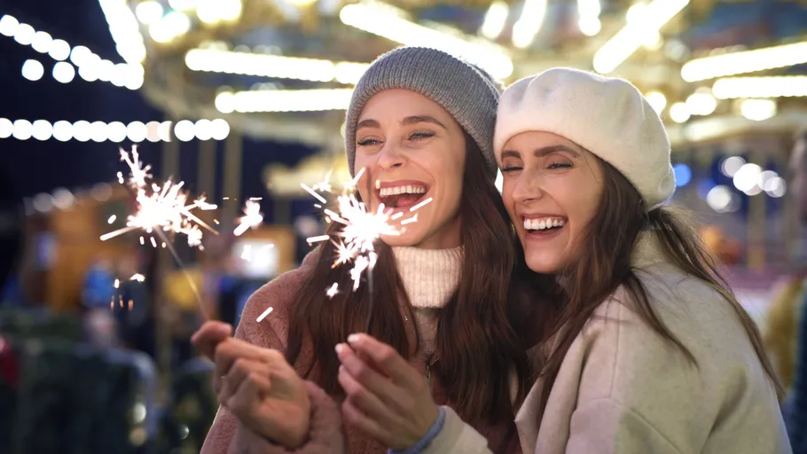 Zwei Frauen halten Wunderkerzen auf einem Jahrmarkt.