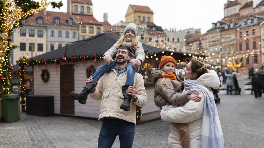 Family enjoying holiday market with festive lights.