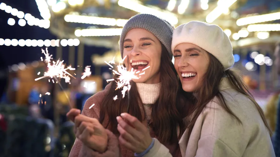 Zwei Frauen halten Wunderkerzen auf einem Jahrmarkt.