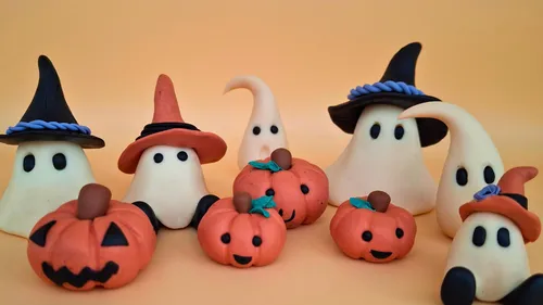 Clay ghosts and pumpkins on orange background.