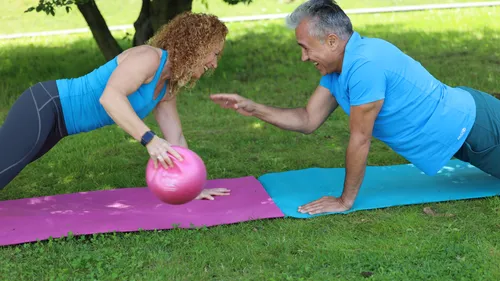 Zwei Personen trainieren auf Matten im Park.