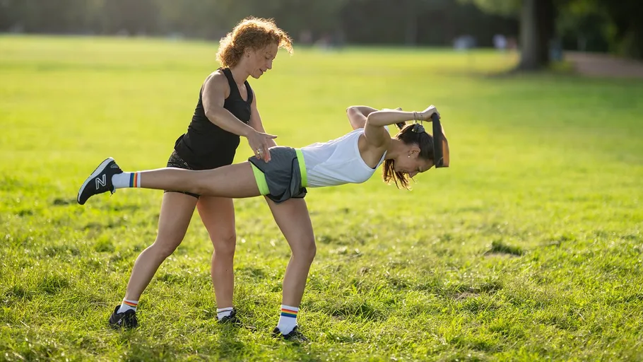 Two women exercising in a sunny park.