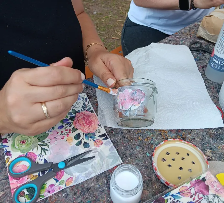 Hands painting jar with floral napkin design.