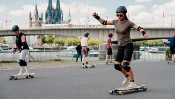 People skateboarding near a bridge in Cologne.