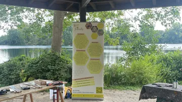 Bee-friendly poster near lake under shelter.