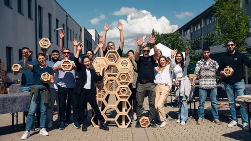 Gruppe hebt Hände mit Holzsechsecken draußen.