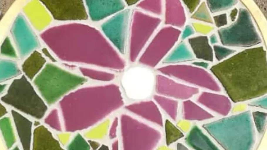Buntes Mosaikblume auf runder Fläche.