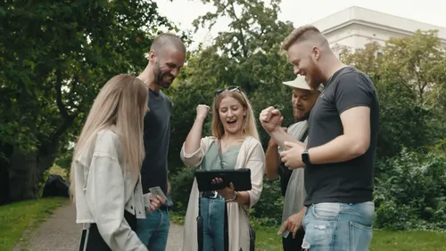 Group celebrating while looking at a device outdoors.