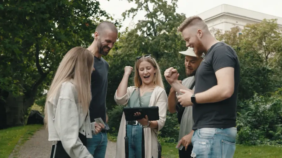 Group celebrating while looking at a device outdoors.