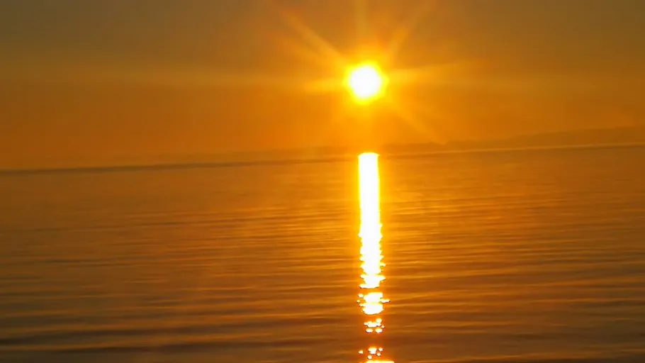 Sun setting over a calm ocean.