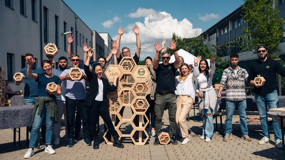 Menschen feiern mit sechseckigen Holzstrukturen draußen.
