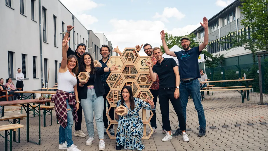 Group of people posing with hexagonal structure outdoors.