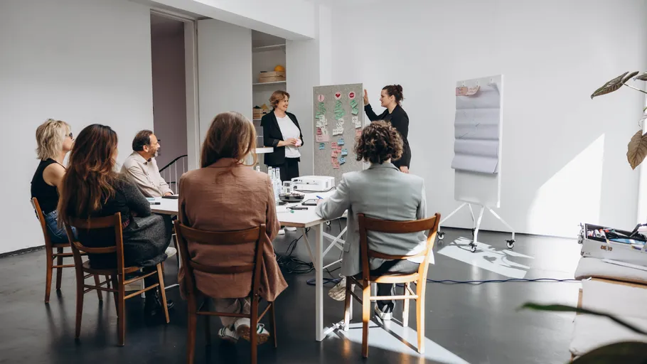 Personen in Besprechung mit Präsentationstafel.
