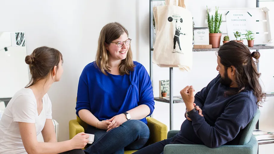 Three people sitting and talking indoors.