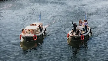 Zwei Boote mit Menschen auf einem Fluss.