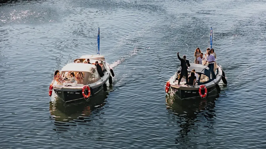 Zwei Boote mit Menschen auf einem Fluss.