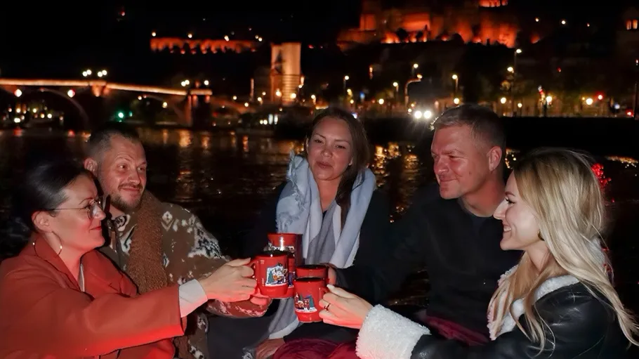 Five people toasting with mugs at night.
