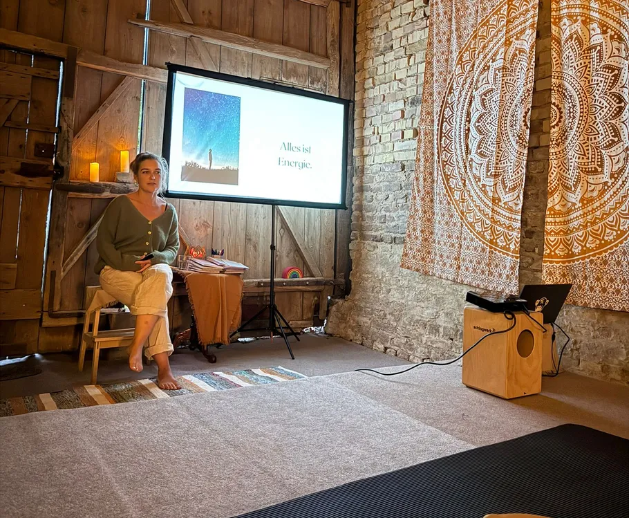Woman sitting beside projected slide in rustic room.