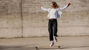 Frau beim Skateboarden, springt im urbanen Bereich.