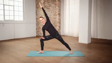 Person in Yoga-Pose auf Matte drinnen.