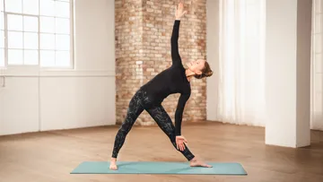 Frau übt Yoga auf Matte im Studio.