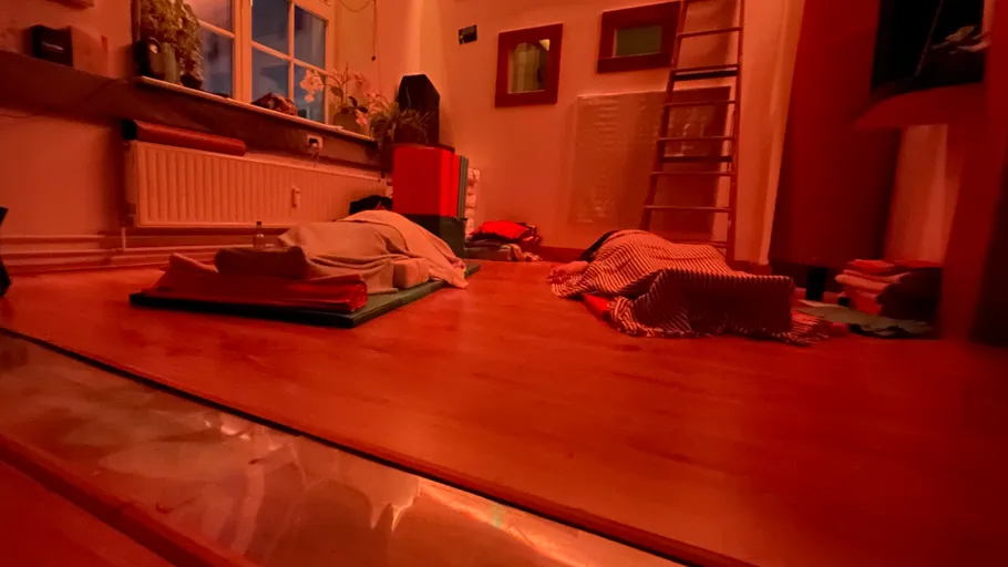 People resting on yoga mats in dimly lit room.