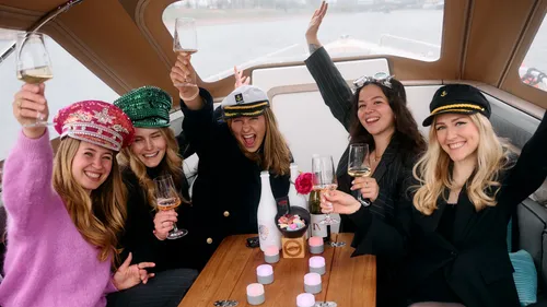 Fünf Frauen heben Gläser auf einem Boot.