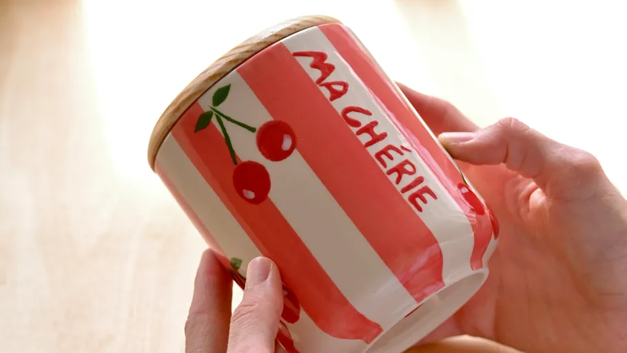 Hands holding striped jar with 'Ma Chérie'.