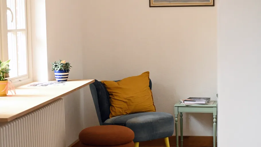 Cozy chair with cushion in bright room.