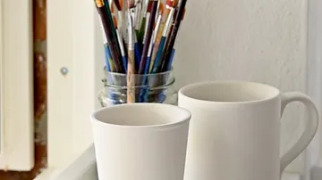 White mugs and brushes on a table.