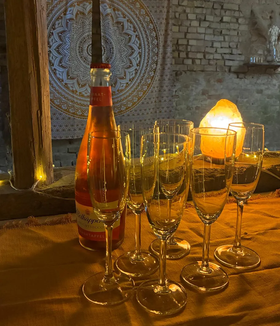Bottle and glasses on a table, candlelight setting.