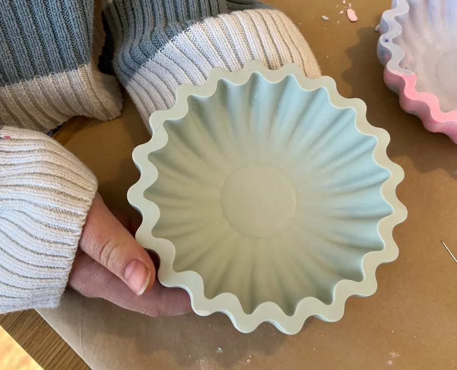 Person holding decorative fluted mold on table.
