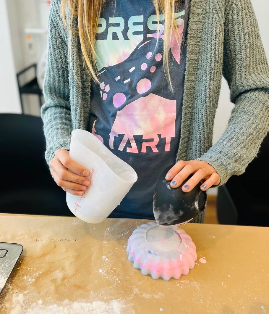 Person pouring mix into mold on table.