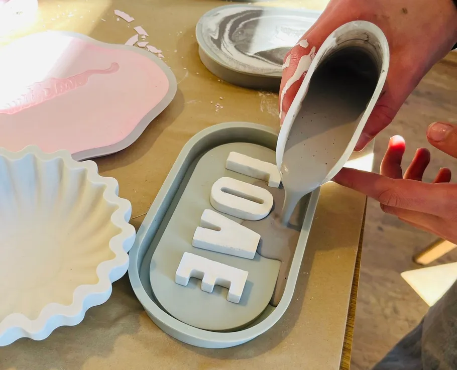 Person pouring plaster into LOVE mold.
