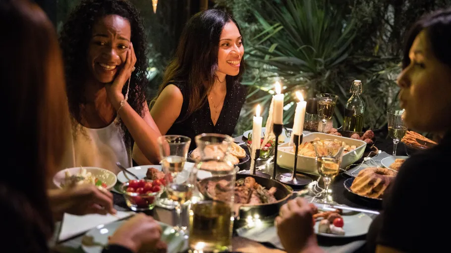 Vier Frauen essen bei Kerzenlicht draußen.