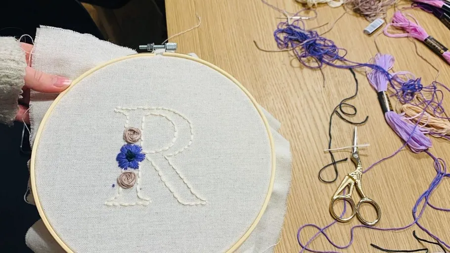 Embroidery of letter R with flowers on cloth.