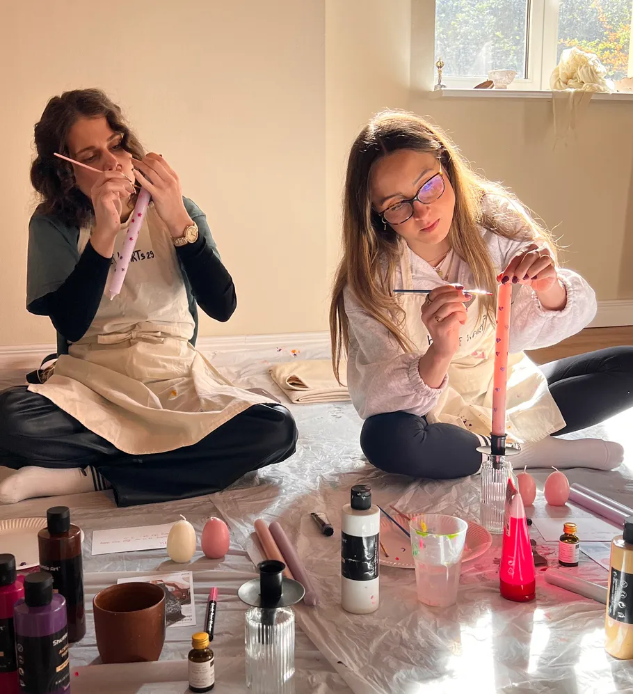 Two women painting candles indoors.