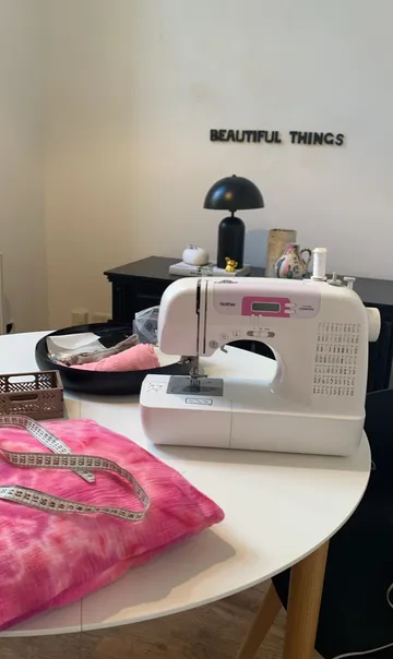 Sewing machine on table with pink fabric.
