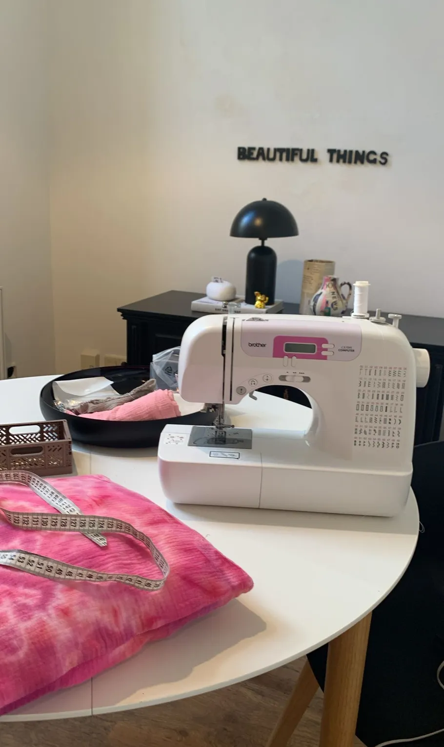 Nähmaschine auf Tisch mit rosa Stoff.