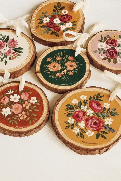 Bemalte Holzscheiben mit Blumendesigns, Bänder befestigt.